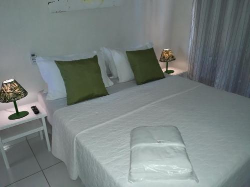 a bedroom with a white bed with green pillows and two lamps at Pousada Casa de Maria Bonita in Arraial d'Ajuda