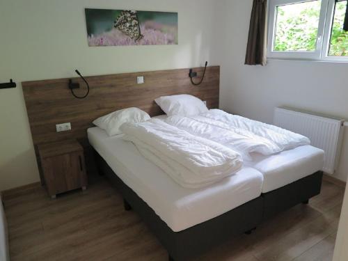 - un lit avec des oreillers blancs dans l'établissement Lovely bungalow in Hoenderloo with fireplace, à Hoenderloo