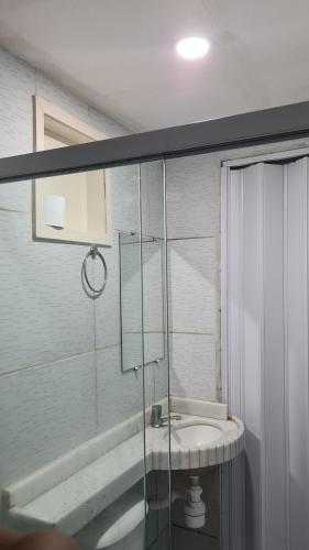 ein Badezimmer mit Waschbecken und Glasdusche in der Unterkunft Apartamento familiar aconchegante in Maragogi