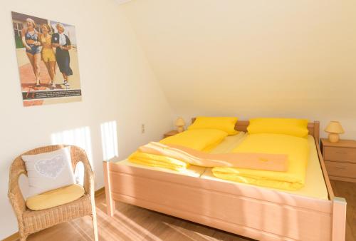 een slaapkamer met een bed met gele lakens en een stoel bij Revenstorf Wohnung 2 in Grömitz