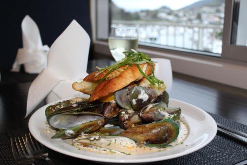 a plate of food with mussels and a glass of water at Beachcomber Inn Picton in Picton