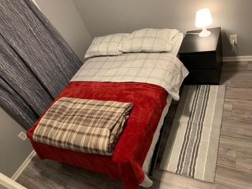 a bedroom with a bed with a red and white blanket at Ottawa airport guesthouse in Ottawa