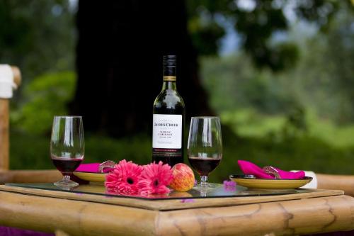 a bottle of wine and two glasses on a table at Aranyak Resort in Tāla