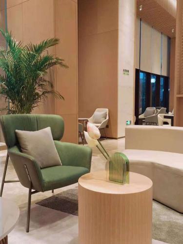 a living room with a green chair and a table at Holiday Inn Luzhou Longjian by IHG in Luzhou