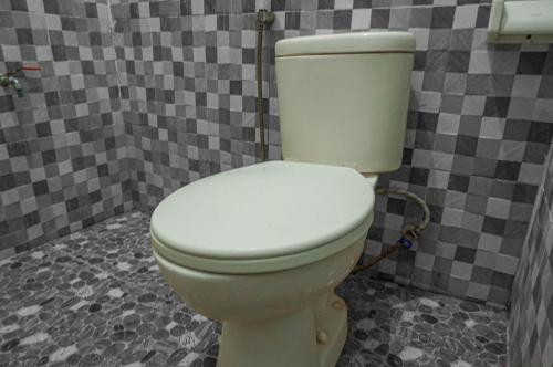 a white toilet in a bathroom with a tile wall at The Wisma Pulau Merah in Pasanggaran