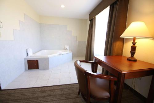 a hotel room with a desk and a bath tub at Crown Pointe Lodge; BW Signature Collection in Farmington