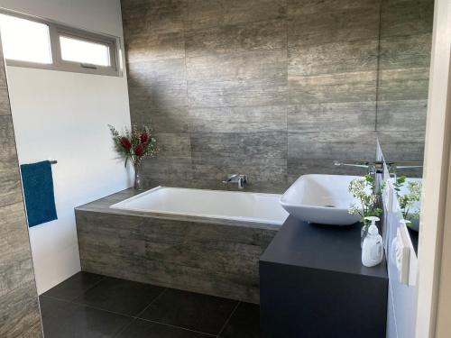 a bathroom with a bath tub and a sink at Sunnyside - Surf Side in Inverloch