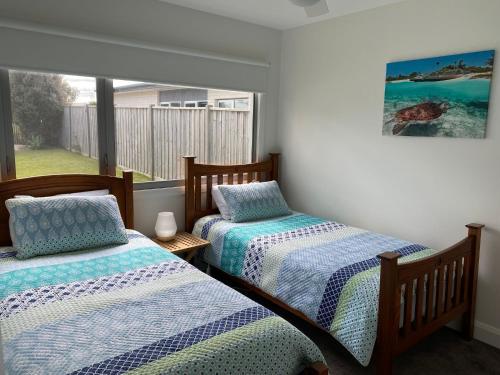 two beds in a room with a window at Sunnyside - Surf Side in Inverloch