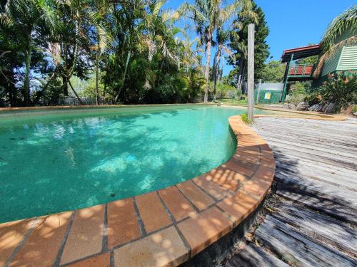 una piscina de agua con terraza de madera en Maiala Park Lodge en Mount Glorious