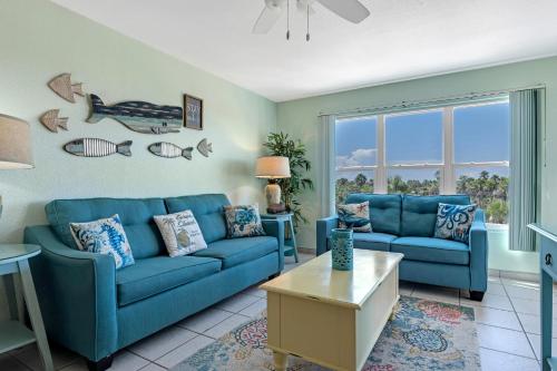 ein Wohnzimmer mit blauen Sofas und einem Tisch in der Unterkunft Charming 1 Bedroom, 3 Minute Walk To The Beach Condo in South Padre Island