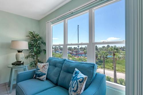 a blue couch in a living room with a large window at Charming 1 Bedroom, 3 Minute Walk To The Beach Condo in South Padre Island