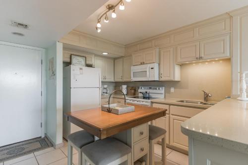 a kitchen with white cabinets and a wooden island with a sink at Charming 1 Bedroom, 3 Minute Walk To The Beach Condo in South Padre Island