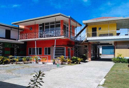 a red and yellow house with a driveway at RedDoorz at EM Pensiontel Butuan City in Butuan