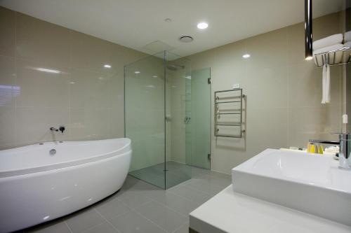 a bathroom with a tub and a glass shower at Hotel 115 in Melbourne