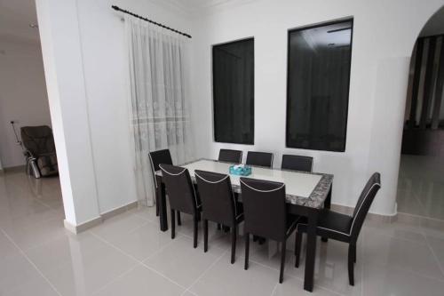 a dining room with a white table and black chairs at Dca villa homestay in Kota Bharu