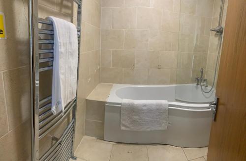 y baño con bañera y toalla. en Beautiful 6 Bedroom with spacious Lounge & Rooms Free parking, en Erith