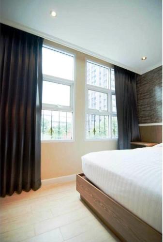 a bedroom with a large bed and two windows at Bourbon St. Boutique Hotel in Bangkok
