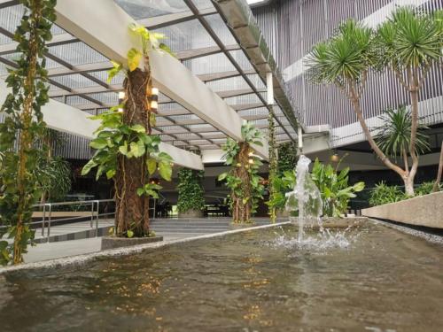 a fountain in the middle of a building with palm trees at Amansari Residence Resort in Johor Bahru