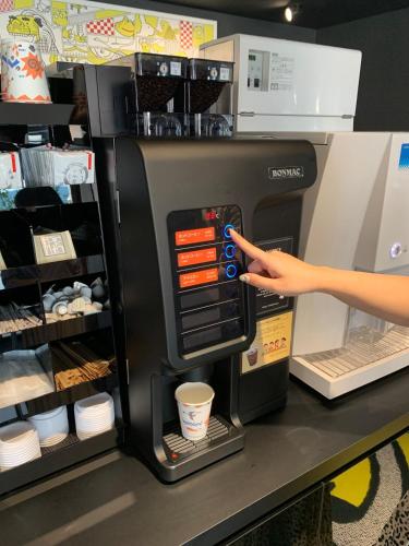 a person is pointing at a coffee machine in a store at HOTEL TAVINOS Kyoto in Kyoto
