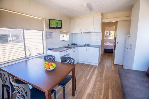 a kitchen with a table with a bowl of fruit on it at Discovery Parks - Pambula Beach in Pambula