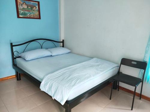 a bed with a black frame and a chair in a room at บ้านเสริมสุข รีสอร์ท หล่มสัก in Wat Pa