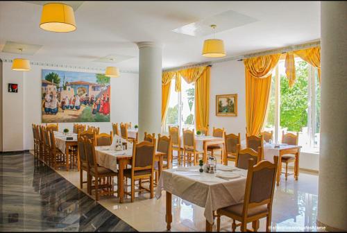 a restaurant with tables and chairs and a painting on the wall at Shkreli Resort Qafeshtame in Krujë