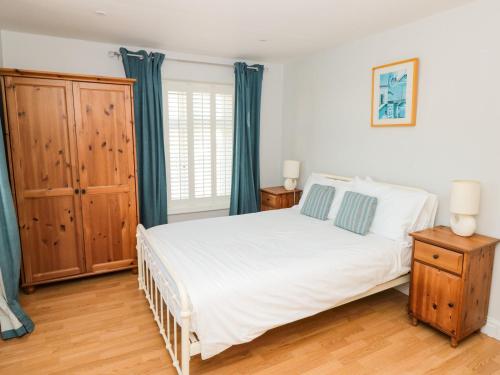 1 dormitorio con cama blanca y cortinas azules en Cindy's Retreat, en Hope-Cove
