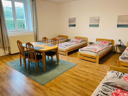 a room with three beds and a table and chairs at Penzion Kelčany u Kyjova in Kelčany