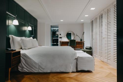 a bedroom with a white bed and a green wall at The Bold Type Hotel, a Member of Design Hotels in Patra
