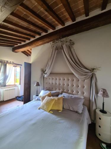 een slaapkamer met een groot wit bed en een baldakijn bij Villa Le Ginestre in Cortona