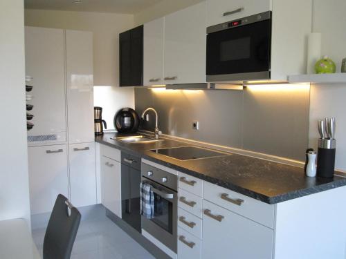 a kitchen with white cabinets and a sink and a microwave at Smucke Stuuv II & III in Glücksburg