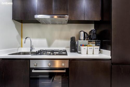 a kitchen with a sink and a stove top oven at bnbmehomes - Merano Tower in Dubai