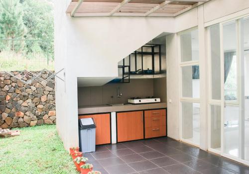 une cuisine extérieure avec des armoires orange et un mur en pierre dans l'établissement The Dago View Bandung, à Bandung