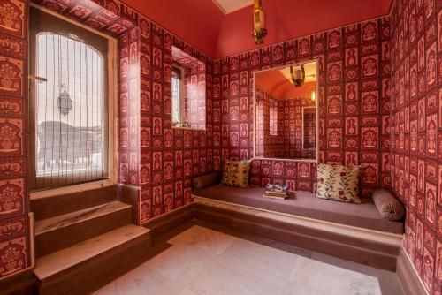 a bathroom with red walls with a bench and a window at Surya Haveli , Amer Fort Jaipur in Jaipur