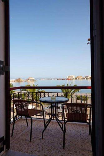 een tafel en stoelen op een balkon met uitzicht op het water bij Aegean Sea Rooms in Chios