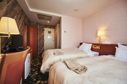 a hotel room with two beds and a flat screen tv at Annex Royal Hotel in Odate