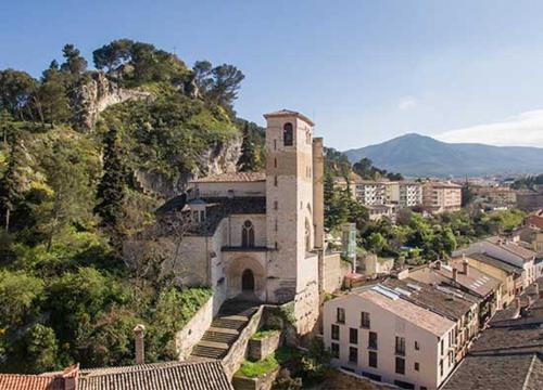 a building with a clock tower on the side of a hill at La Casa de los Mil Años in Estella