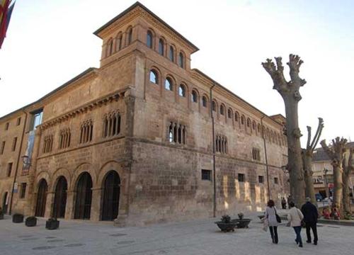 a large brick building with people walking in front of it at La Casa de los Mil Años in Estella
