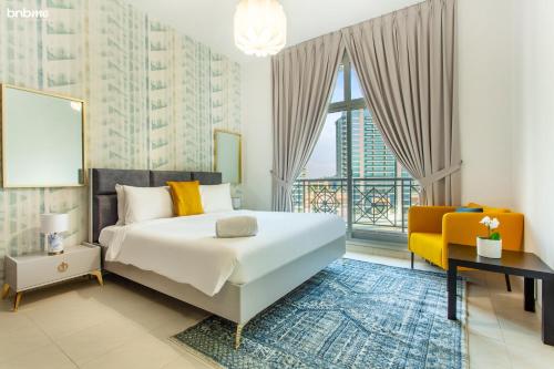 sypialnia z dużym łóżkiem i żółtym krzesłem w obiekcie bnbmehomes - Elegant Apt In Al Barsha South - 613 w Dubaju