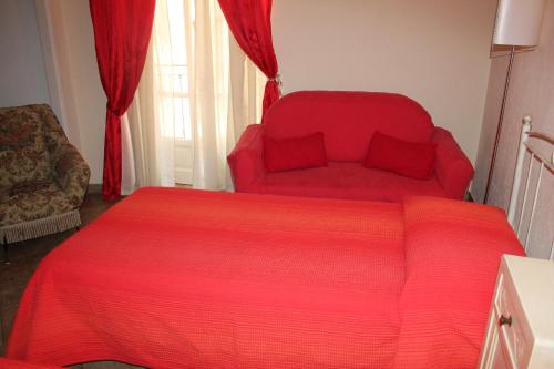 a bedroom with a red bed and a red couch at Hotel Porta Santa Maria in Busca