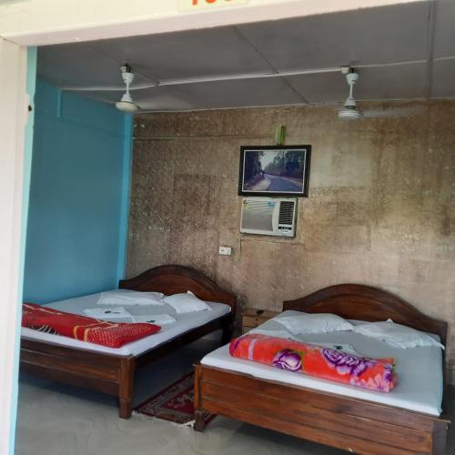two twin beds in a room with a wall at Gorumara Nature's Cottage (A Unit Of M/S Ecological & Tours) in Jalpāiguri
