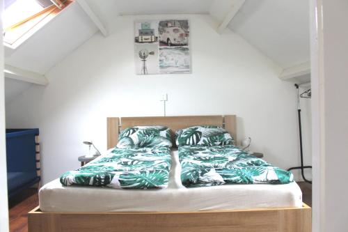a bedroom with a bed with green and white sheets at Ammophila 2 in Egmond aan Zee