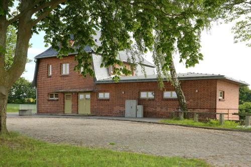 a red brick building with a tree in front of it at Bahnhof Hohen Mistorf in Hohen Mistorf