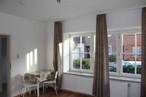 ハイリゲンハーフェンにあるHaus Wagner App 1の窓2つ、テーブルと椅子が備わる客室です。