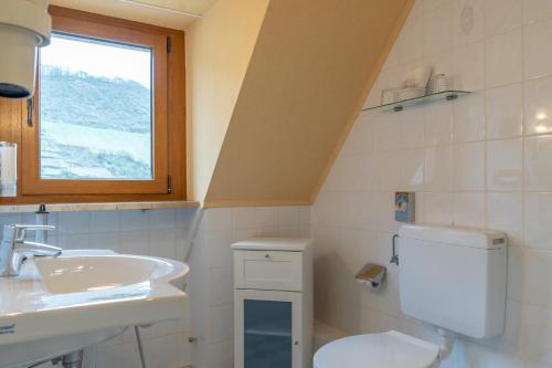 a bathroom with a toilet and a sink and a window at Weinhotel Landsknecht in Sankt Goar