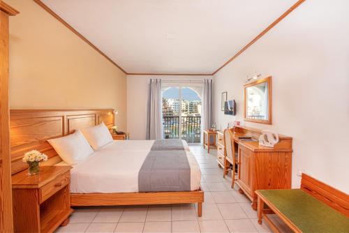 a bedroom with a bed, a desk, and a window at Gillieru Harbour Hotel in St. Paul's Bay