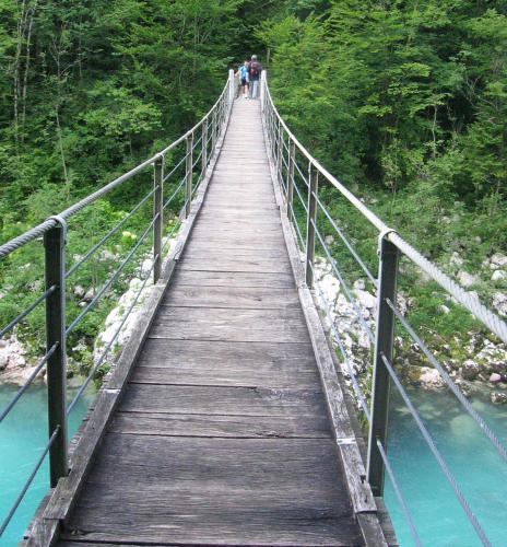 a bridge over a river with two people walking on it at Apartment Mars in Bovec