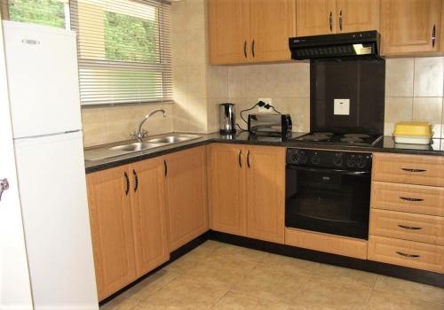 a kitchen with wooden cabinets and a black appliance at Cozumel 212 in Umdloti