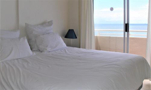 a white bed with a view of the beach at Cozumel 212 in Umdloti