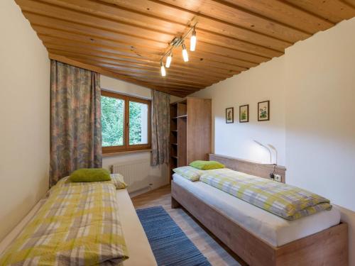 a bedroom with two beds and a wooden ceiling at Haus am Waldesrand in Ellmau